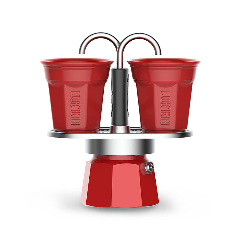 Red Bialetti espresso maker with two cups on a white background. Italian Moka