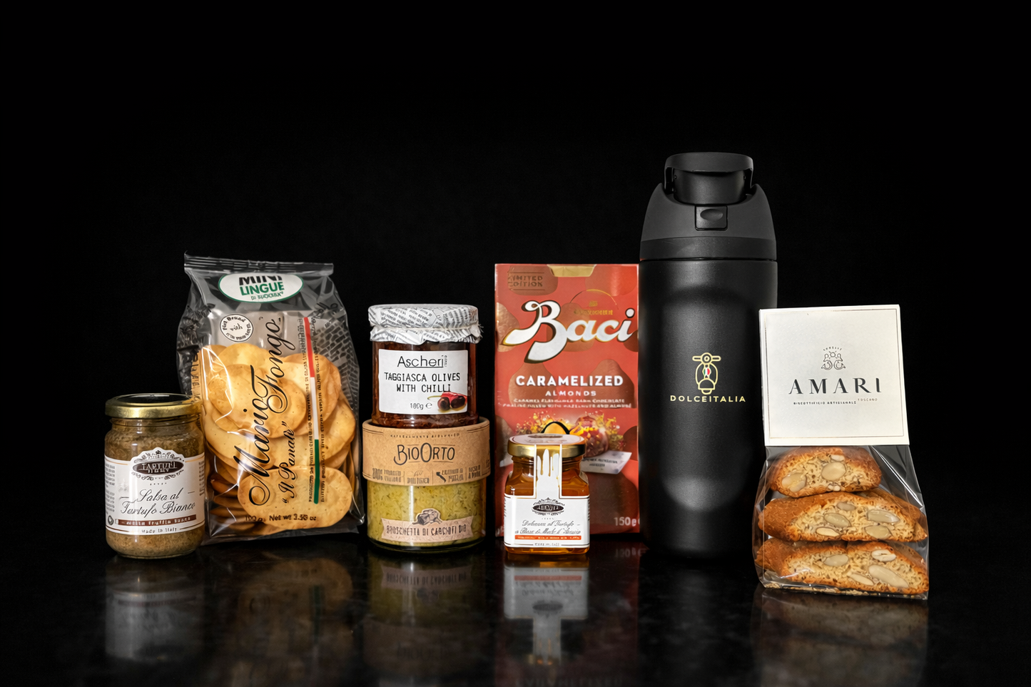 Collection of snacks, drinks, and products on a dark surface with a black background. Italian gourmet hampers australia. italian hampers online 