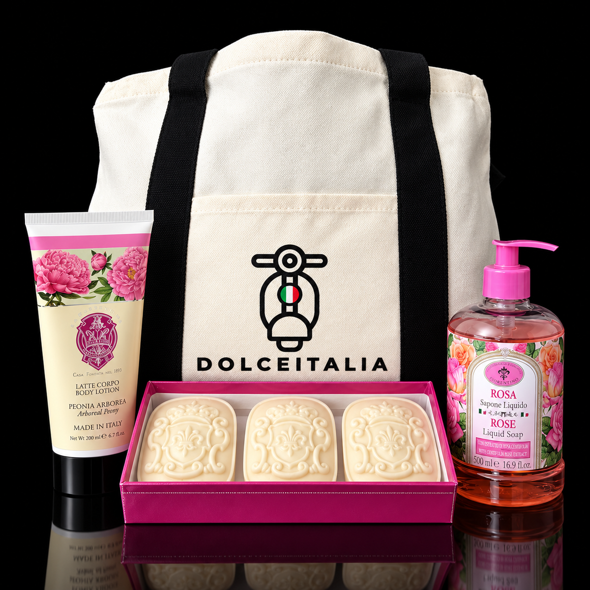 DolceItalia gift set featuring a cream canvas tote bag with black straps and logo, a tube of body lotion, a boxed set of three soap bars, and a bottle of liquid soap, all arranged on a black reflective background. italian gifts australia