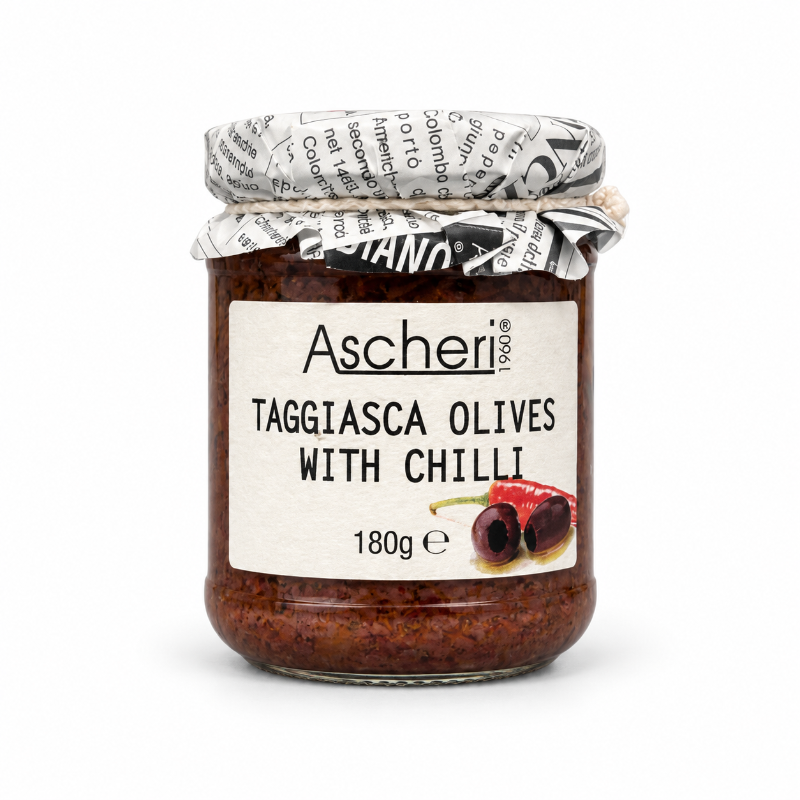 A glass jar of Ascheri Taggiasca Olives with Chilli, showing the dark red olives inside, sealed with a newspaper-patterned paper lid and a white label.