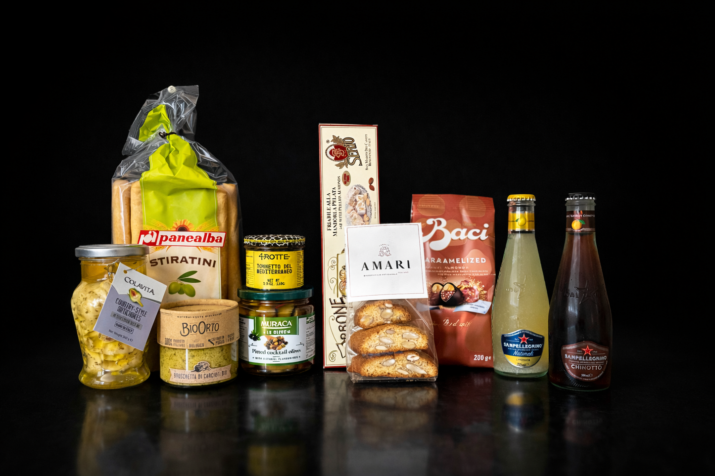 Assorted food products including jars, bottles, and boxes on a black background. Italian gourmet hampers. 