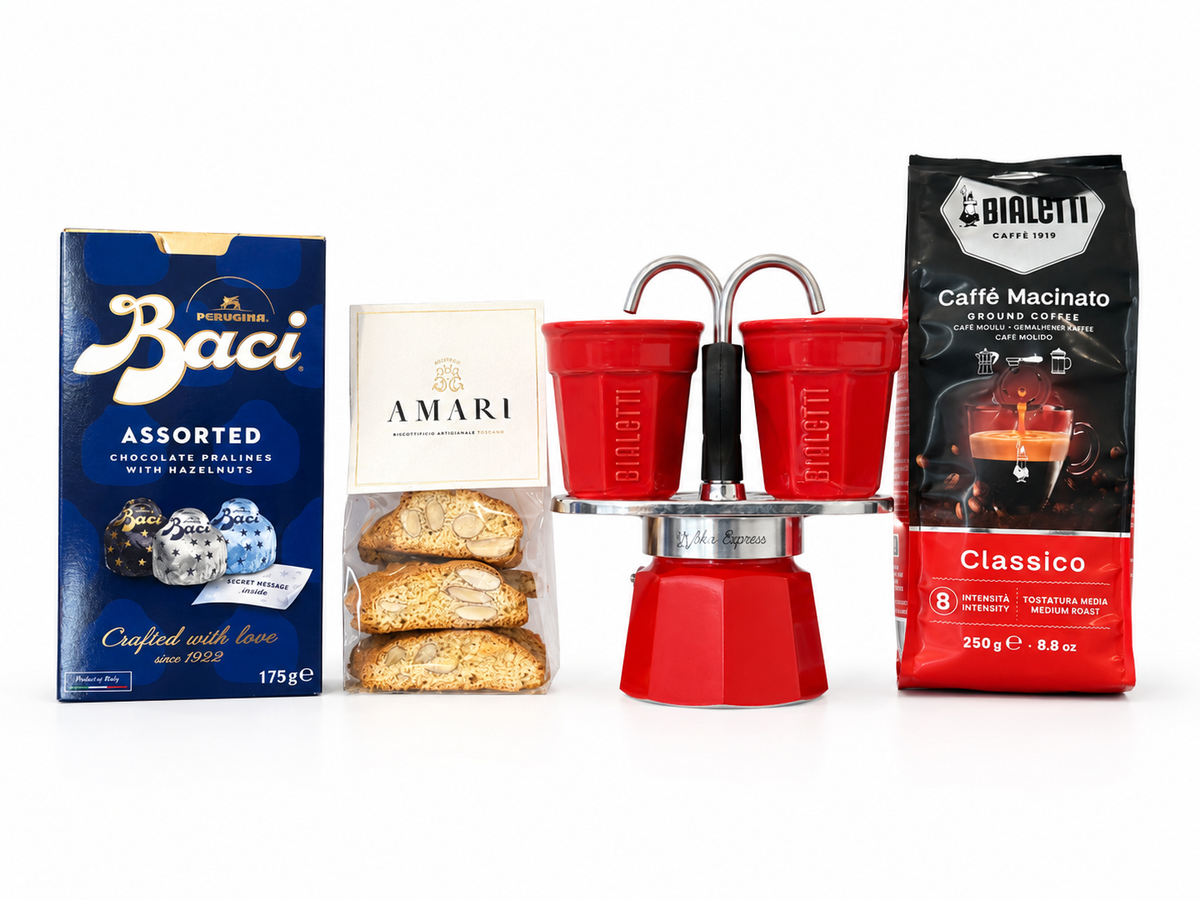 A curated collection of Italian snacks and coffee gear on a white background, featuring a blue box of Baci Assorted chocolate pralines, a box of Amari biscotti, a red Bialetti moka pot, a red Bialetti coffee cup set, and a bag of Bialetti Caffé Macinato Classico.